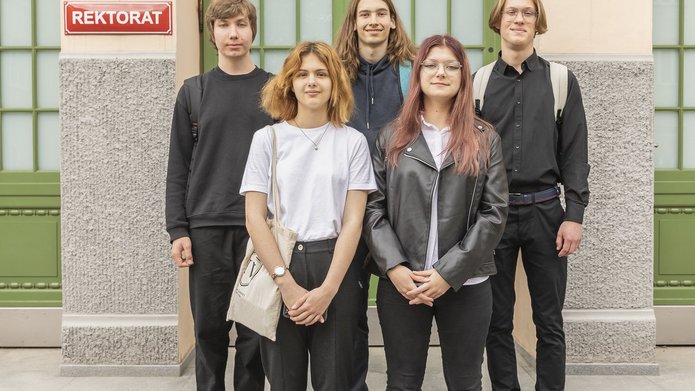 5 uczniów stojących przed budynkiem Rektoratu UŁ