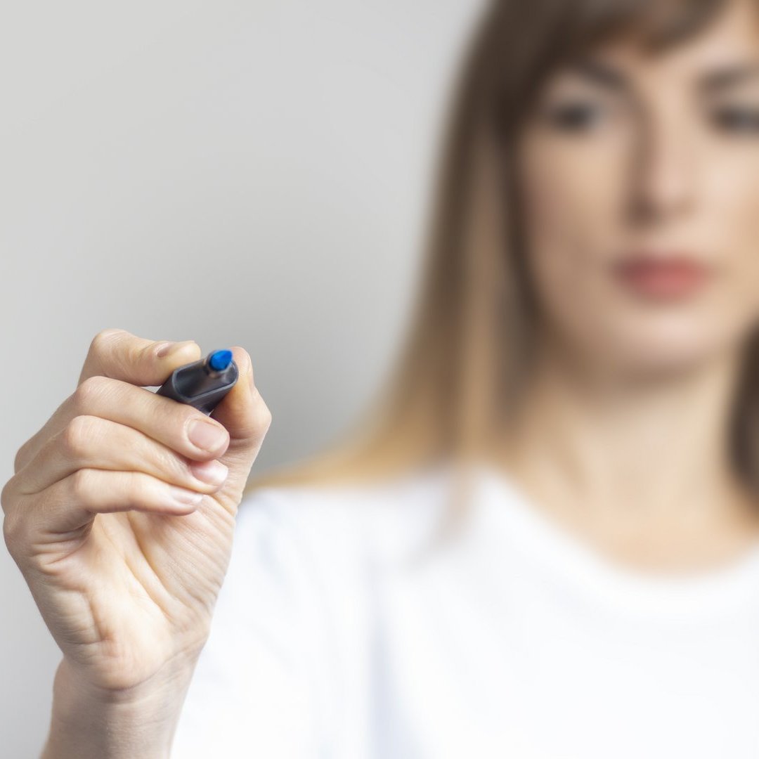 Young woman holds a blue marker and writes something on a light background. Banner Element dekoracyjny