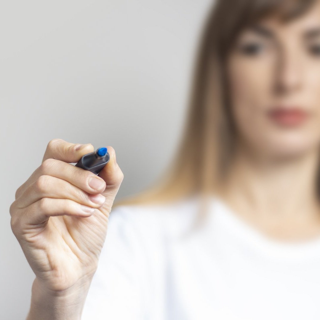 Young woman holds a blue marker and writes something on a light background. Banner Element dekoracyjny