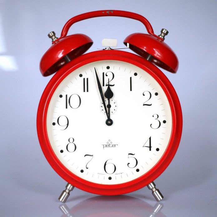 A red clock showing time: almost midnight