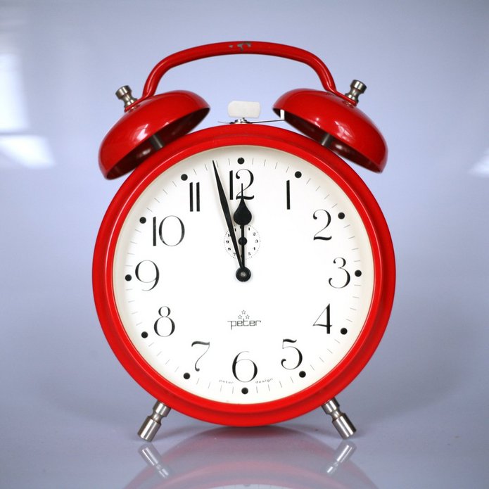 Czerwony budzik, wskazówki na za trzy dwunasta.