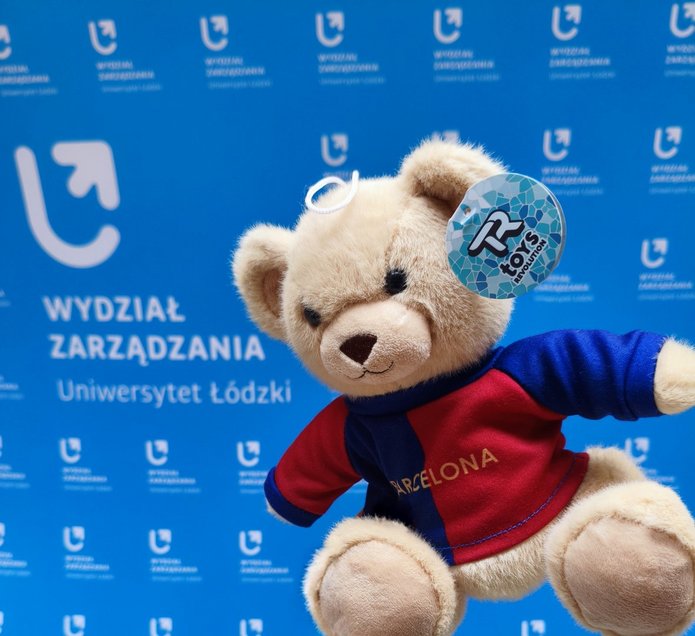 a teddy bear against the background of the banner of the Faculty of Management, University of Lodz