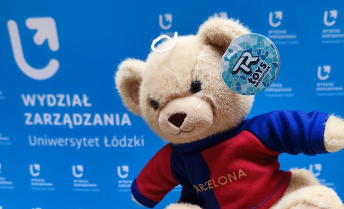 a teddy bear against the background of the banner of the Faculty of Management, University of Lodz