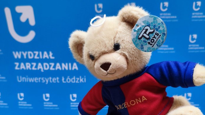 pluszowy miś na tle ścianki Wydziału Zarządzania UŁ