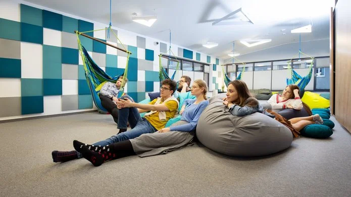 Zdjęcie wnętrza sali relaksu w CWiD UŁ. Na hamakach i pufach siedzą uśmiechnięci młodzi ludzie