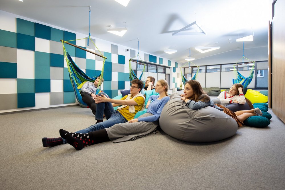 Zdjęcie wnętrza sali relaksu w CWiD UŁ. Na hamakach i pufach siedzą uśmiechnięci młodzi ludzie