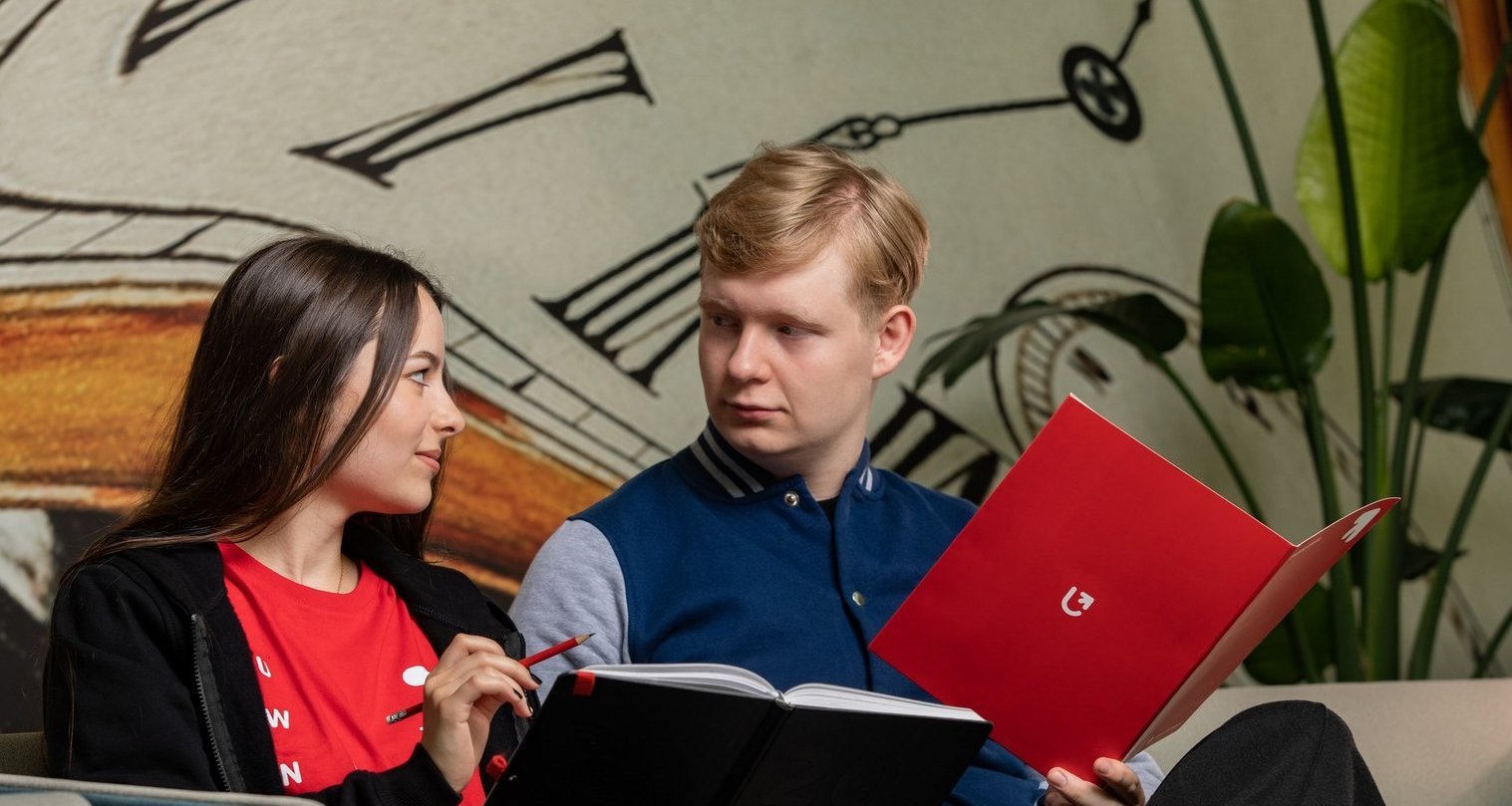 Studenci siedzą na kanapie z notatkami.