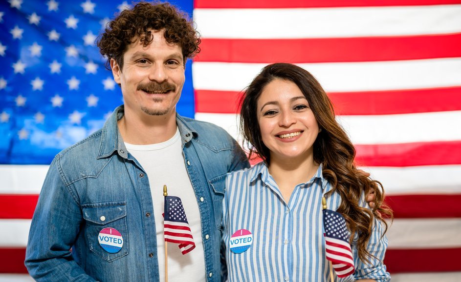 Kobieta i mężczyzna zachęcający do udziału w wyborach na tle amerykańskiej flagi.