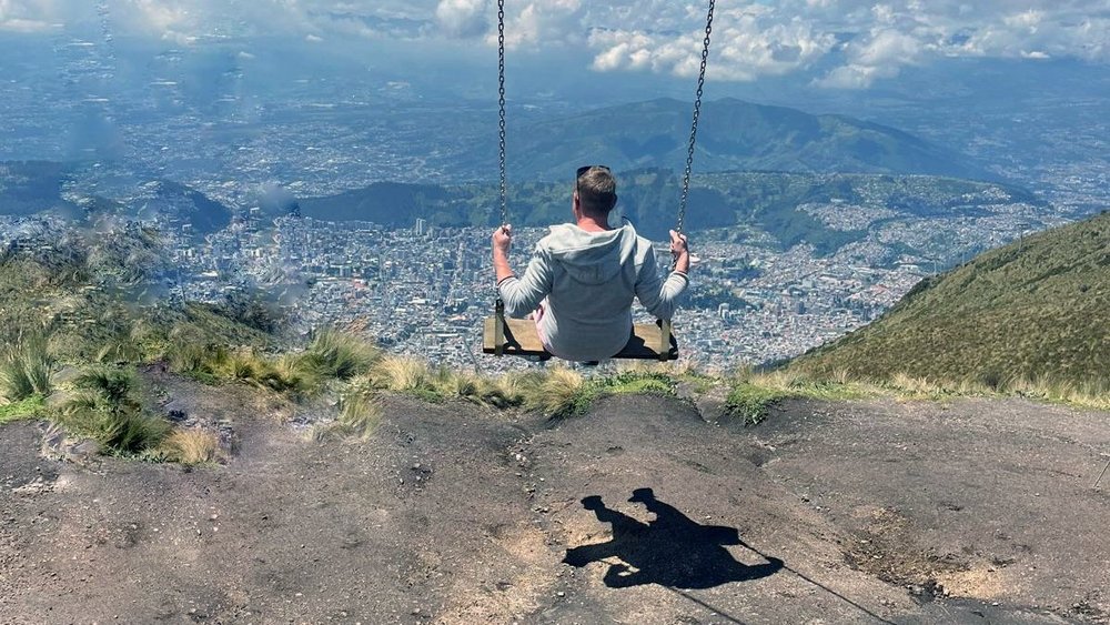 A man on a swing, with a city skyline in the background