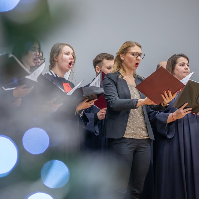 Chór Akademicki UŁ - Kobiety i mężczyźni śpiewający, trzymający nuty