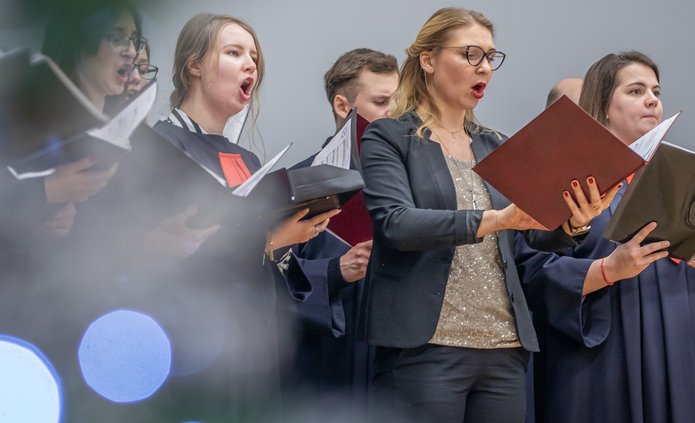 Chór Akademicki UŁ - Kobiety i mężczyźni śpiewający, trzymający nuty