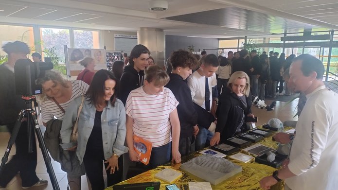 uczestnicy Pikniku naukowego, grupa uczniów i nauczycieli obserwująca stoisko z pokazami fizycznymi