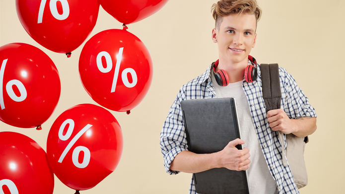 Na zdjęciu widać mężczyznę. Stoi przodem do nas, w prawej dłoni trzyma dokumenty i laptop, przez lewe ramię przewieszony ma plecak. Po jego prawej stronie widać balony w kolorze czerwonym, które mają biały symbol procent nadrukowany na powierzchni. Balony unoszą się w powietrzu.