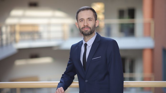 dr Artur Modliński pozuje na tle Wydziału 