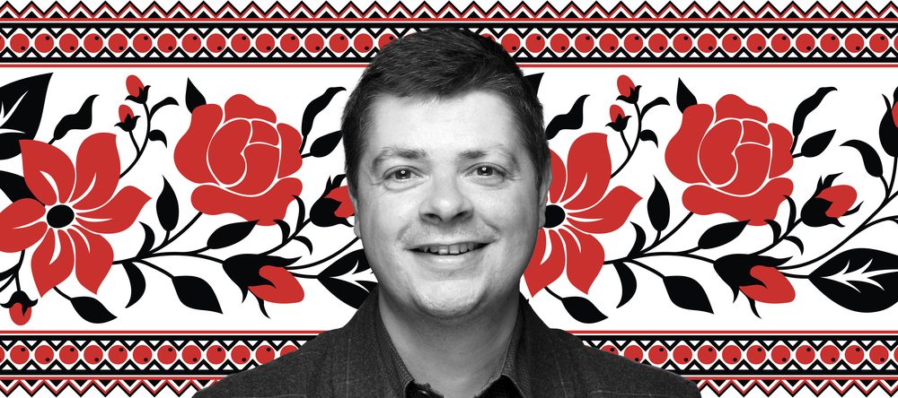 Dr Tomasz Lachowski na białym tle wypełnionym wzorem w czerwone kwiaty z czarnymi liśćmi