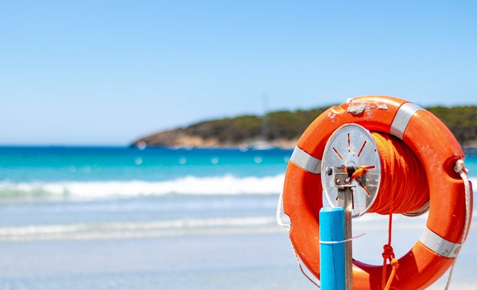 Na pierwszym planie koło ratunkowe, w tle widok na morze.