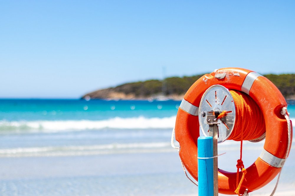 Na pierwszym planie koło ratunkowe, w tle widok na morze.