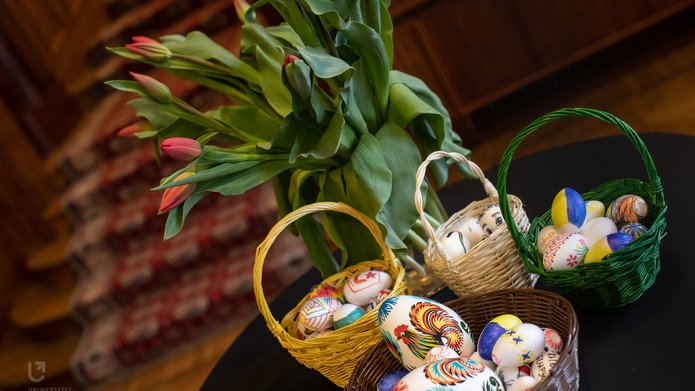 pisanki w koszyczkach i czerwone tulipany w wazonie