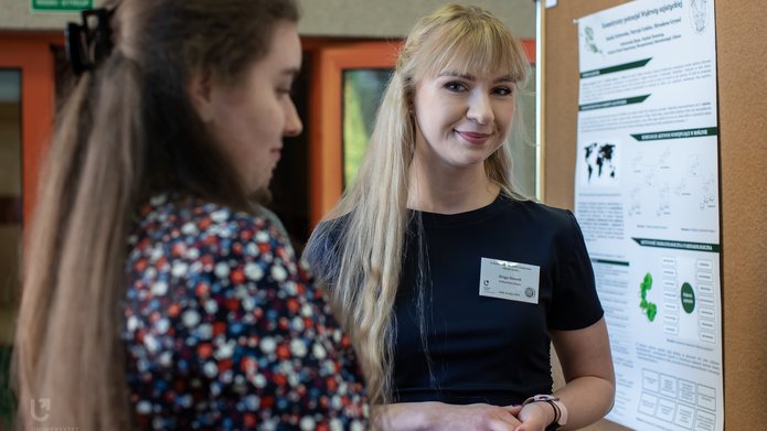 Dwie młode kobiety stojące przy tablicy z plakatem