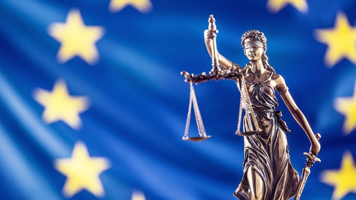 Rzeźba Temidy na tle flagi UE.
