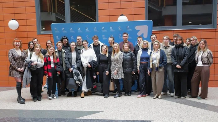 A group of people in front of the banner of the Faculty of Management of the University of Lodz