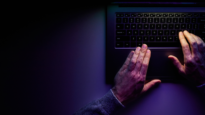 Ciemne tło. Dłonie na klawiaturze laptopa