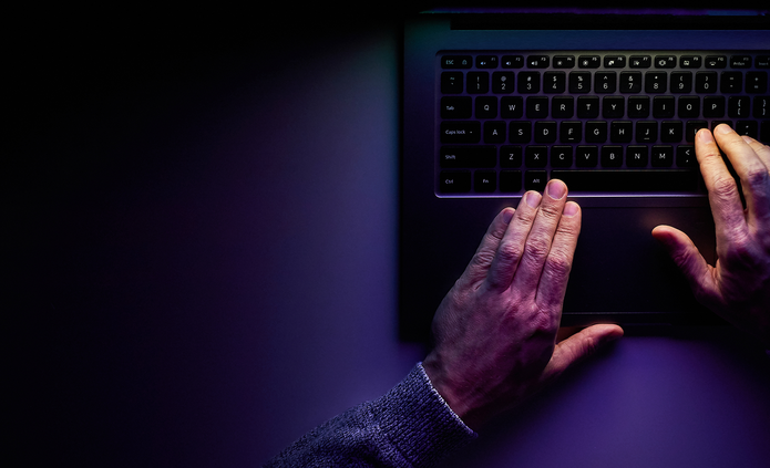 a decorative element: Dark background. Hands on a laptop keyboard