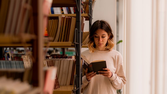 A girl reading a book in a library
