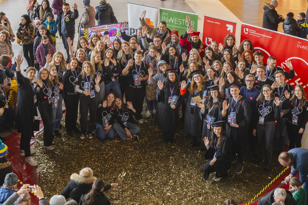 Students and employees of the University of Lodz standing in front of a heart made of gold coins