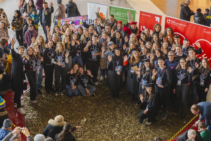 Students and employees of the University of Lodz standing in front of a heart made of gold coins