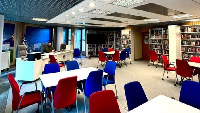 American Corner Łódź. Na pierwszym planie stoły i czerwone oraz niebieskie krzesła.