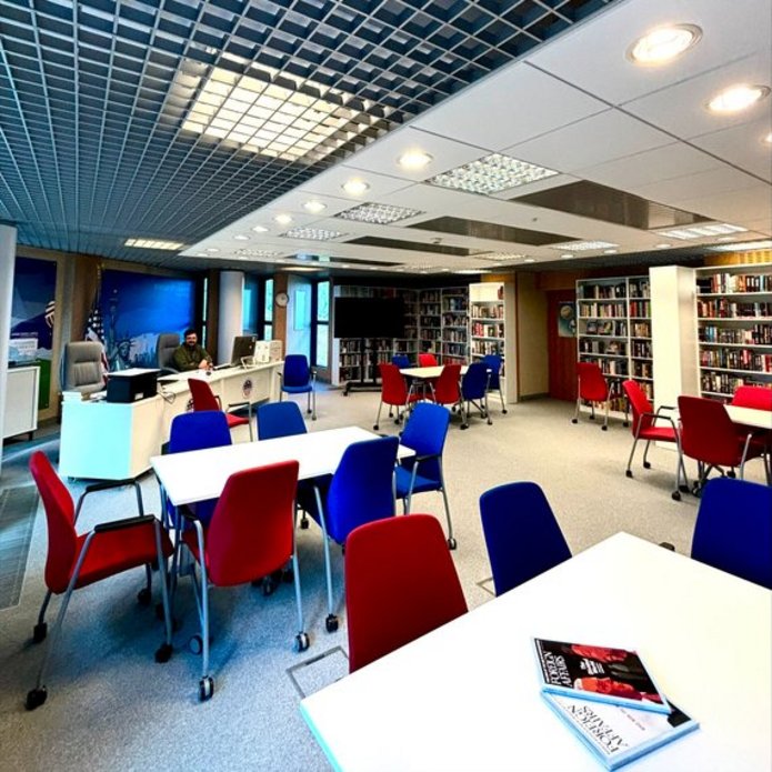 American Corner Łódź. Na pierwszym planie stoły i czerwone oraz niebieskie krzesła.