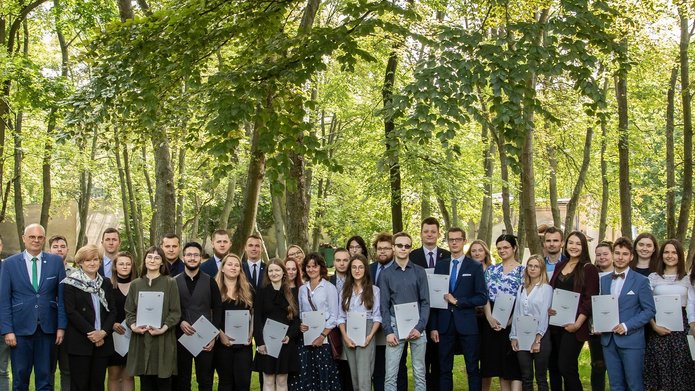 Zdjęcie grupowe wyróżnionych studentów i Władze UŁ n tle drzew 