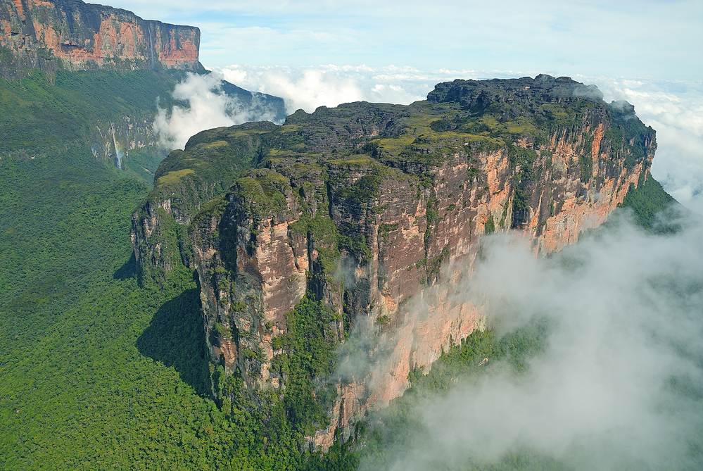 A view of huge rock massifs surrounded by greenery and partly shrouded in clouds