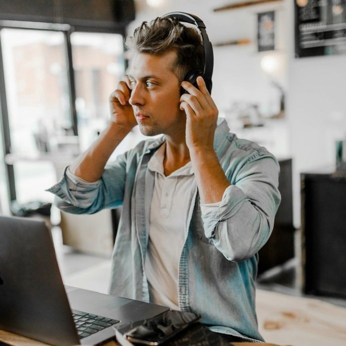 Chłopak zakłada słuchawki., obok włączony komputer. Zdjęcie poglądowe.