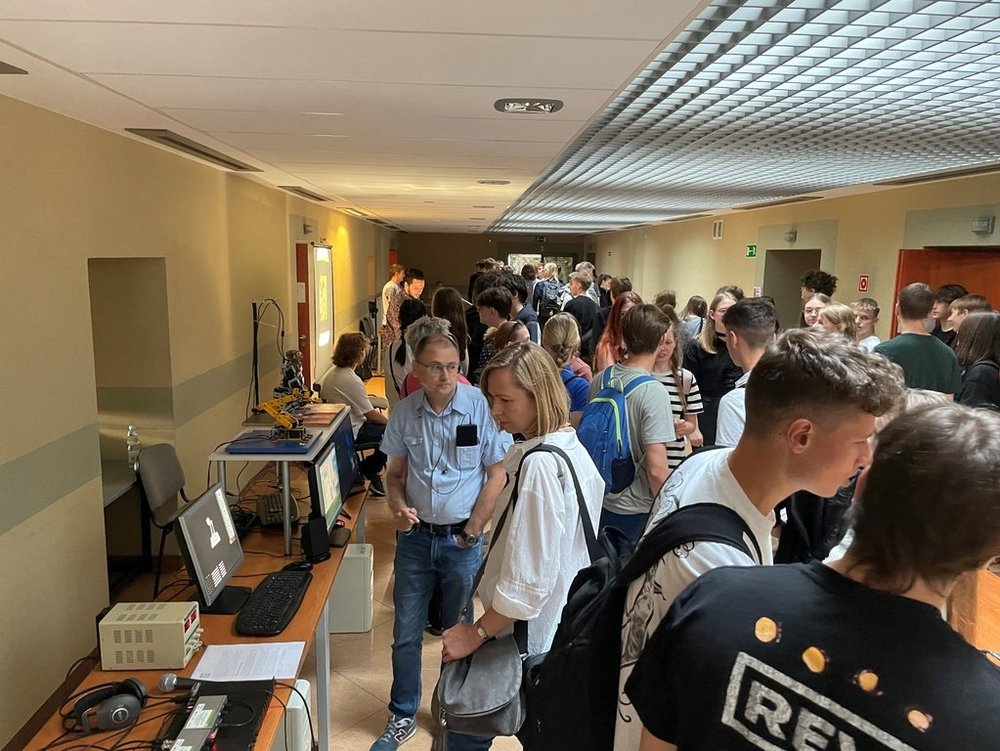 w korytarzu uczestnicy spotkania oglądają pokazy fizyczne na stoiskach