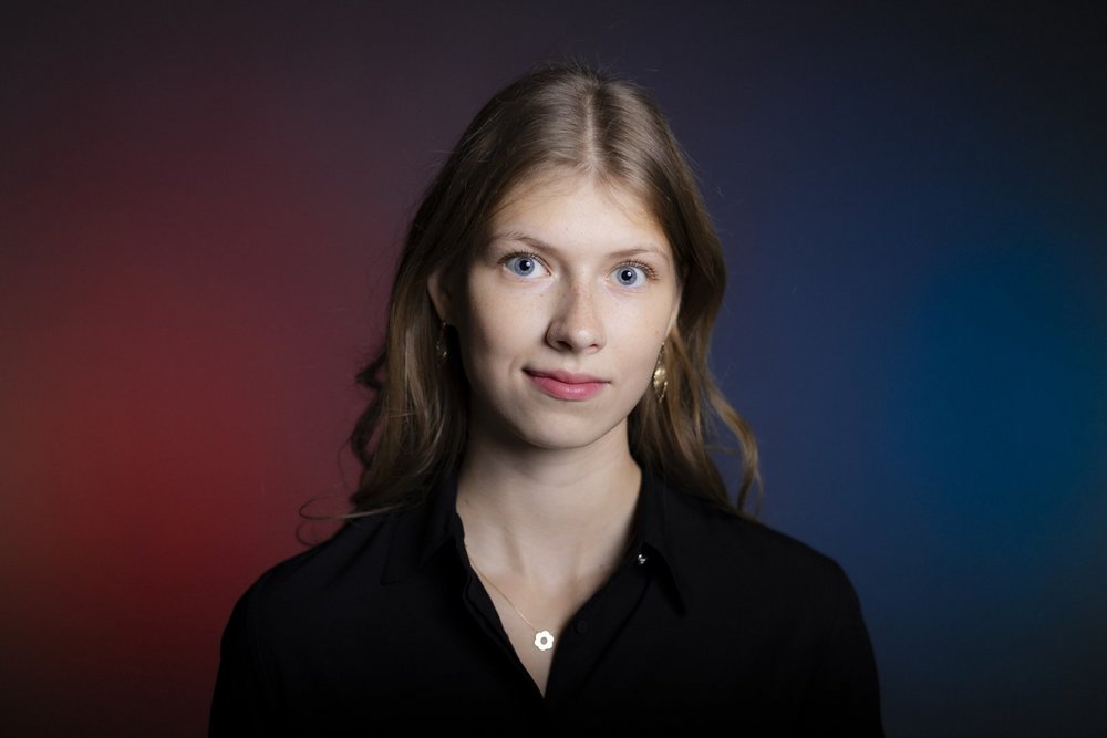 Blond dziewczyna z długimi włosami na tle fioletowo granatowej ściany