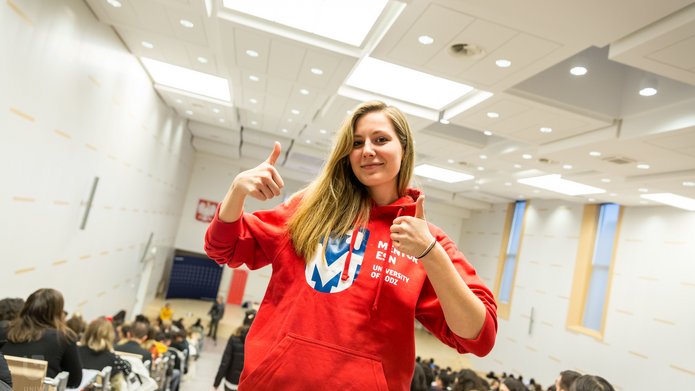 Dziewczyna unosząca kciuki w górę w bluzie Uniwersytetu Łódzkiego