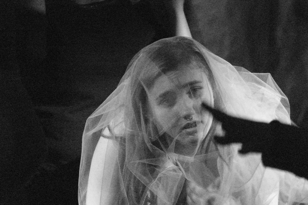 A still from the performance, a black and white photograph, a woman in a wedding dress looking straight ahead