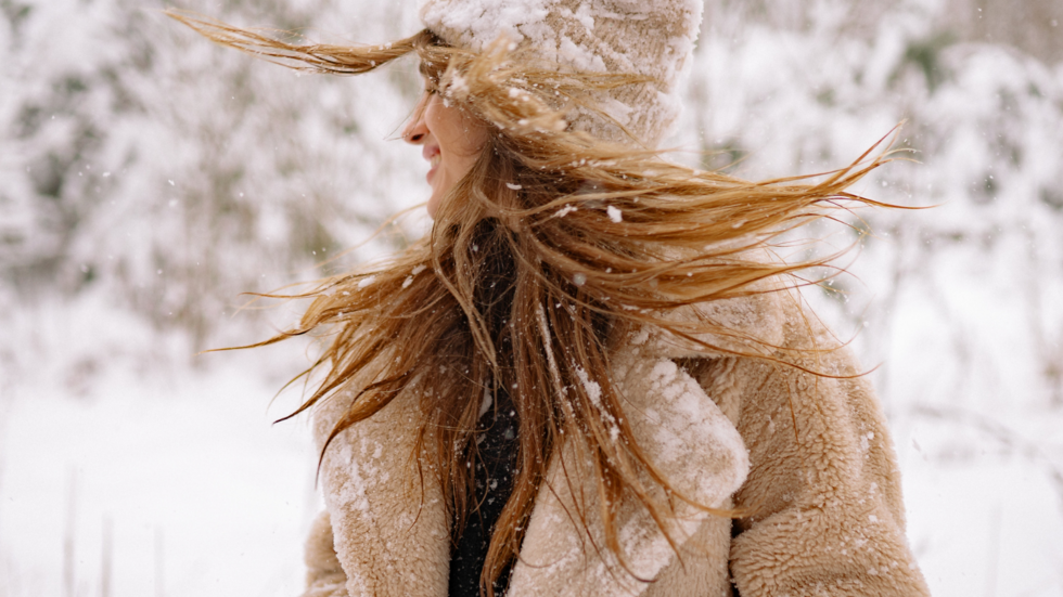 uśmiechnięta kobieta w zaśnieżonym płaszczu