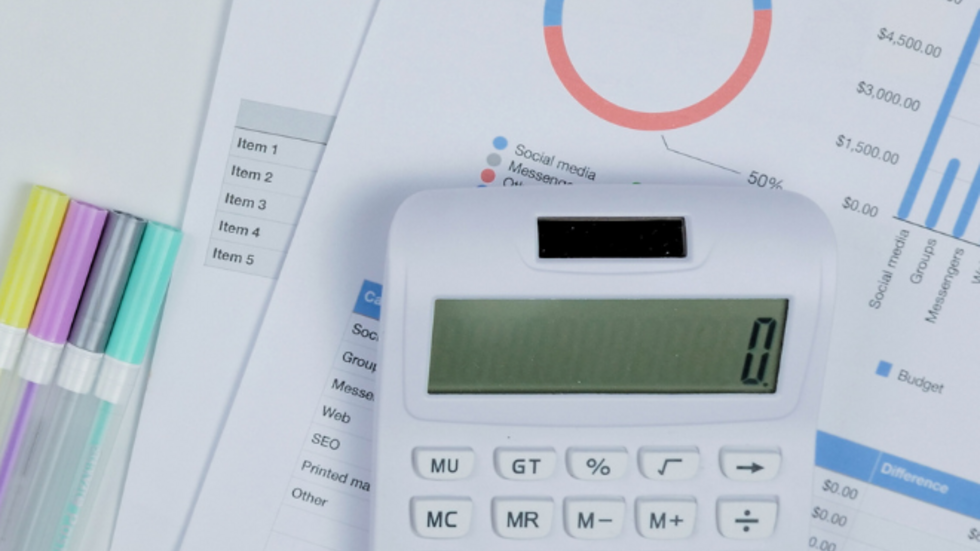 kartki z wykresami, flamastry oraz kalkulator leżące na szarym stole