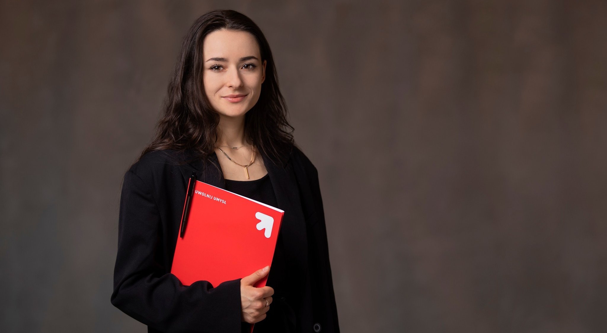 Studentka trzymająca czerwoną teczkę z dokumentami. 