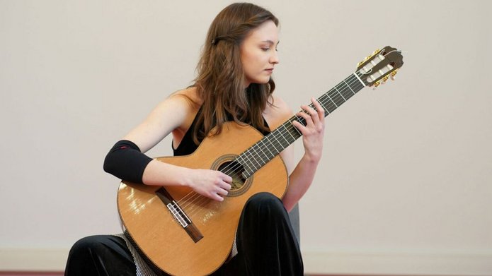 Kalina Polańska who is sitting and playing the guitar