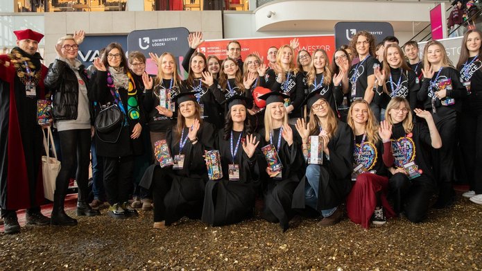 Grupa osób - studenci i Władze UŁ stojący na wielkim sercu ze złotych monet