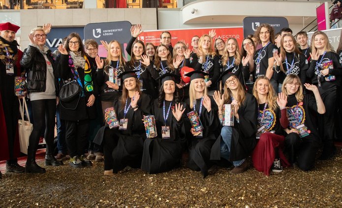 Grupa osób - studenci i Władze UŁ stojący na wielkim sercu ze złotych monet