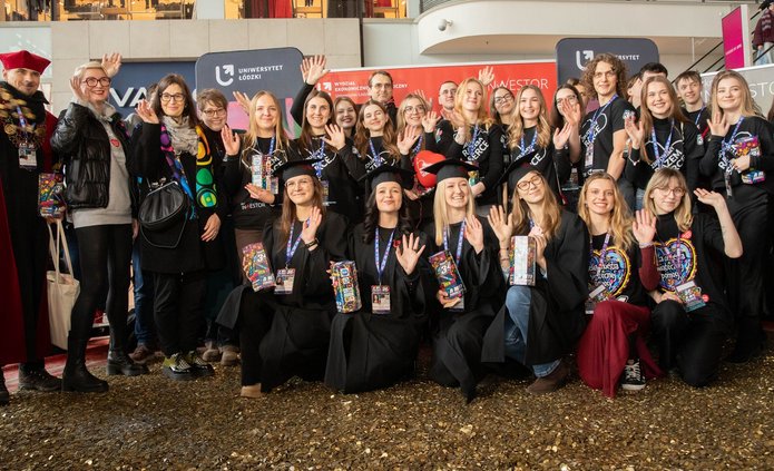 Grupa osób - studenci i Władze UŁ stojący na wielkim sercu ze złotych monet