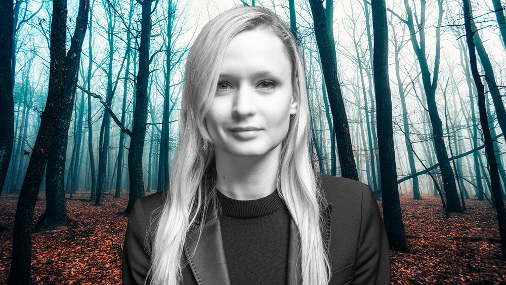 Dr Marta Jabłońska na tle lasu rozświetlonego jasnoniebieskim światłem