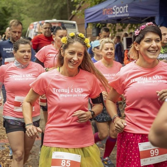 Grupa ludzi biegnie przez las w zawodach sportowych