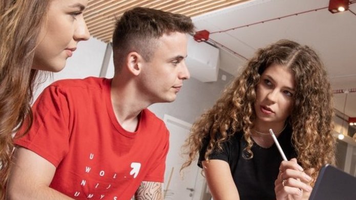 Studentki i student rozmawiają przy laptopie