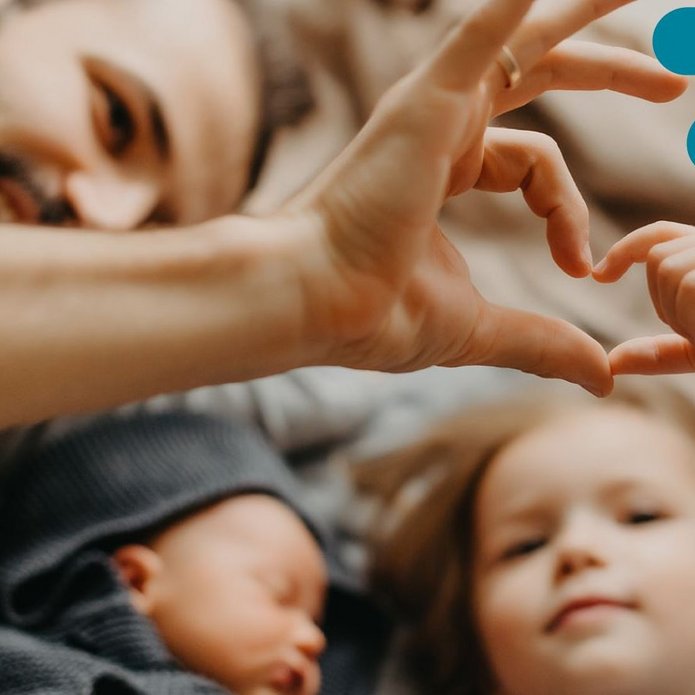 tata z córką formują z dłoni serce, obok mniejsze dziecko